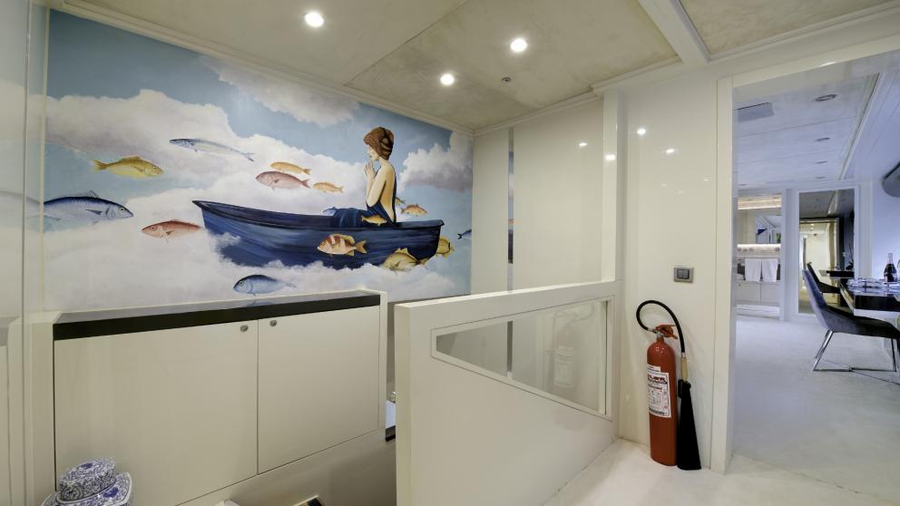 A painting of a woman on the clouds across the entire wall decorates the hallway of the luxury yacht.